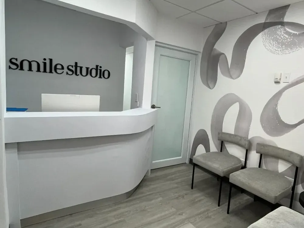 The Smile Studio reception desk beneath the studio wordmark, with the waiting-area chairs beside it