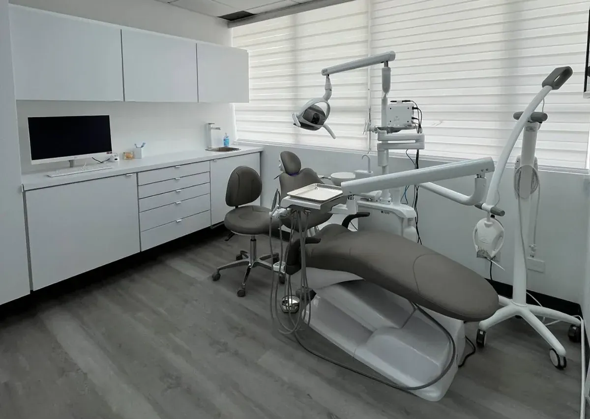Un cuarto de tratamiento de Smile Studio: el sillón, la lámpara y un monitor al lado del sillón sobre gabinetes blancos