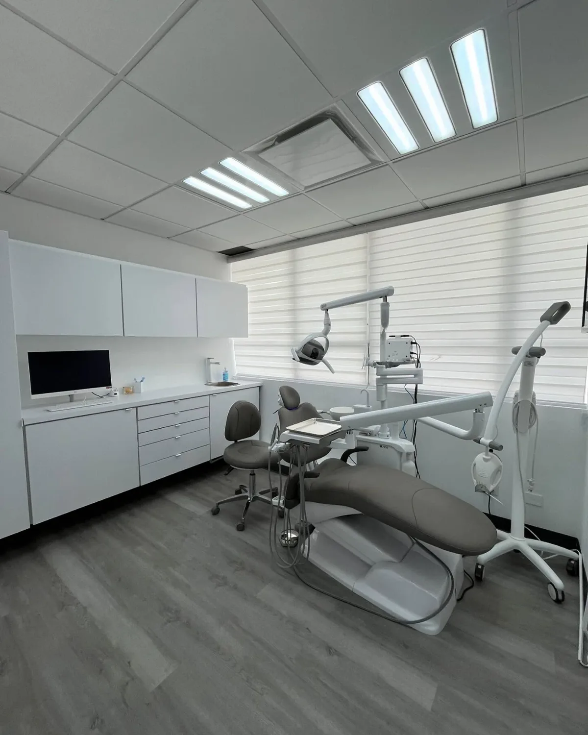 A Smile Studio treatment room: dental chair, overhead light and a chairside monitor against white cabinetry