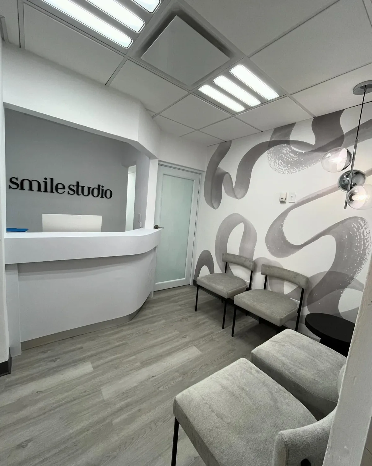The Smile Studio reception: a curved white desk beneath the studio's wordmark, with a grey mural along the waiting-area wall